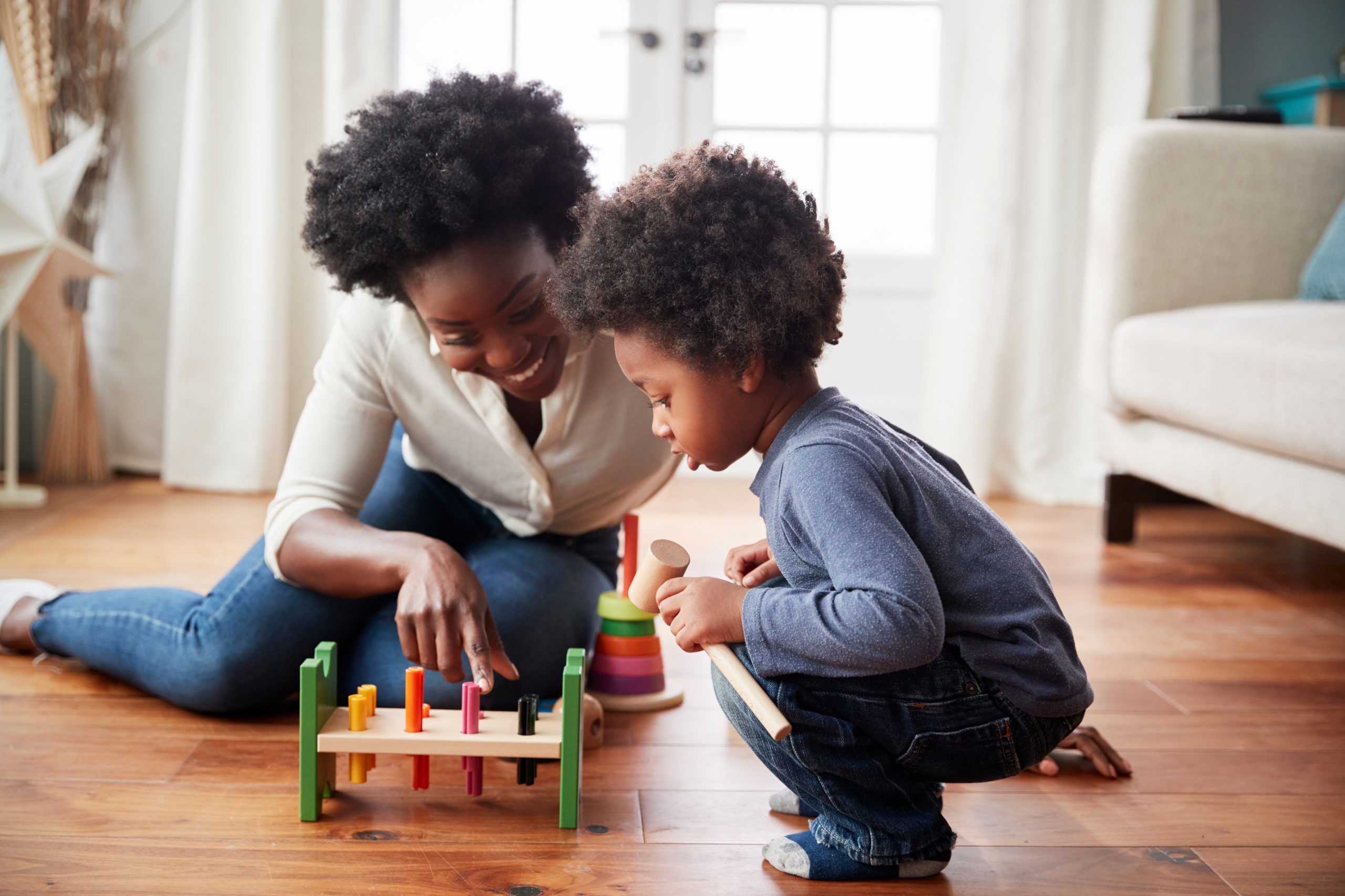 Mother And Young Son Playing With Wooden Toy At Home.
