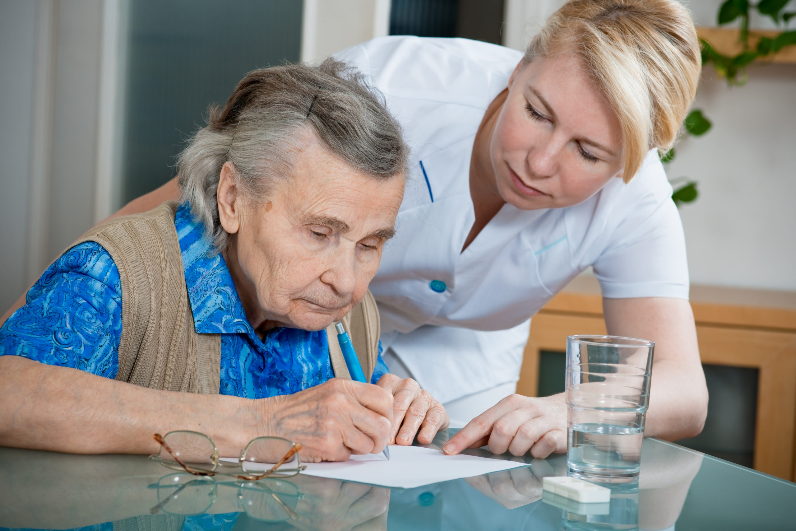 Nurse helping older lady to write