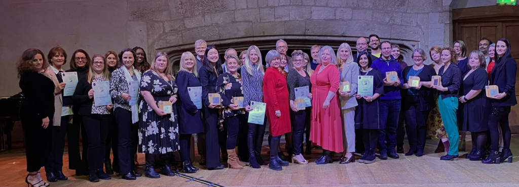 A crowd of people pose for a photo to celebrate their award wins