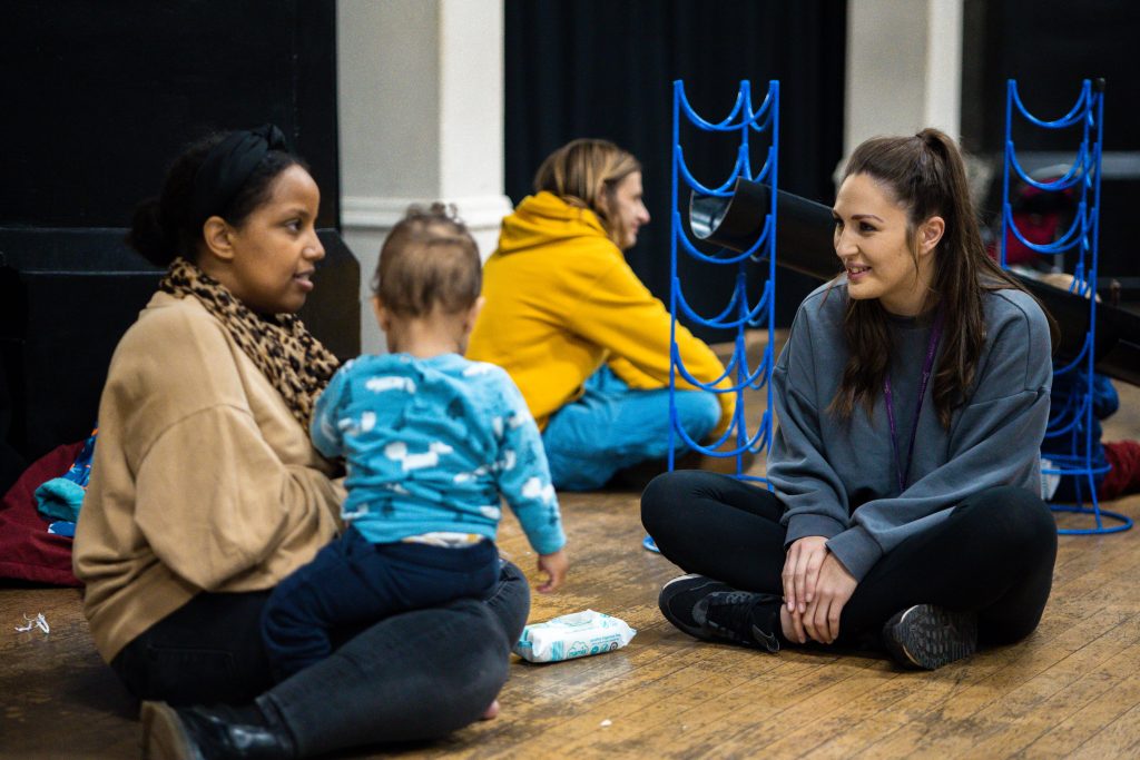 Mother and child talking to a health visitor at a baby hub.