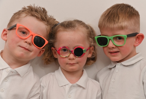 Three primary school children wearing glasses.