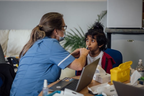 A child receiving the flu vaccine as a nasal spray from a member of Sirona's immunisation team.