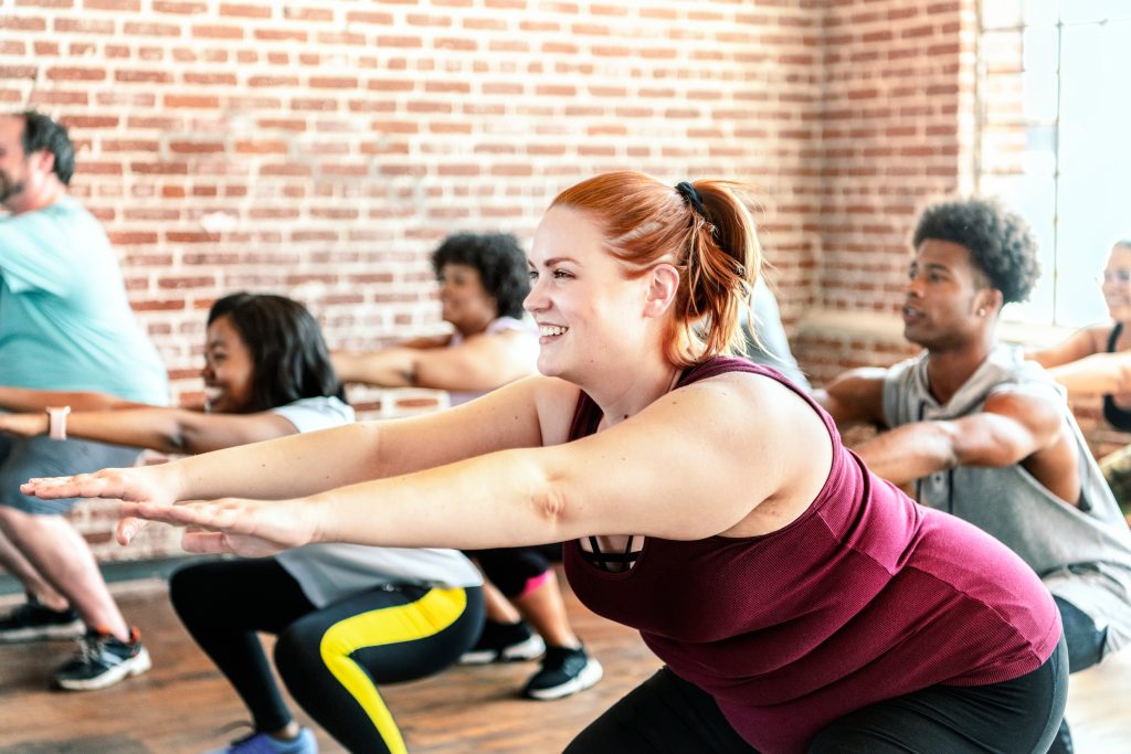 Men and women doing squats in a sports hall during an exercise class.