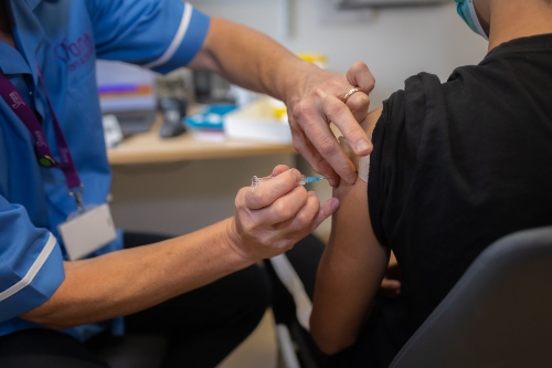 Teenage boy receiving vaccination in upper arm.