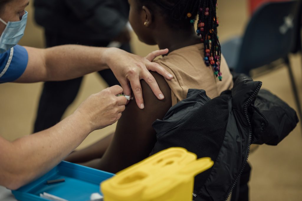 Teenager receiving vaccination in her upper arm.