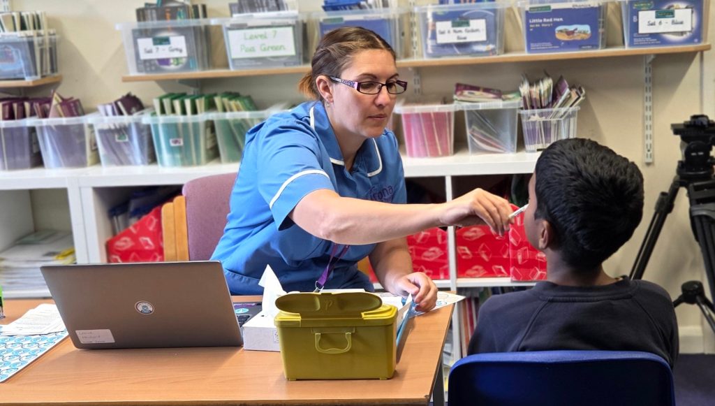 Child receiving the flu vaccine nasal spray at school.