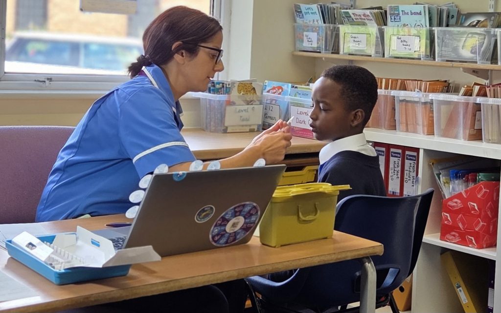 A child receiving the nasal flu vaccine from a member of our School Aged Immunisation Team.