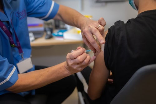 Teenage boy receiving a vaccination in his upper arm.