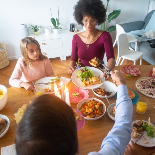 A warm family dinner scene with candles and diverse members sharing a meal indoors.